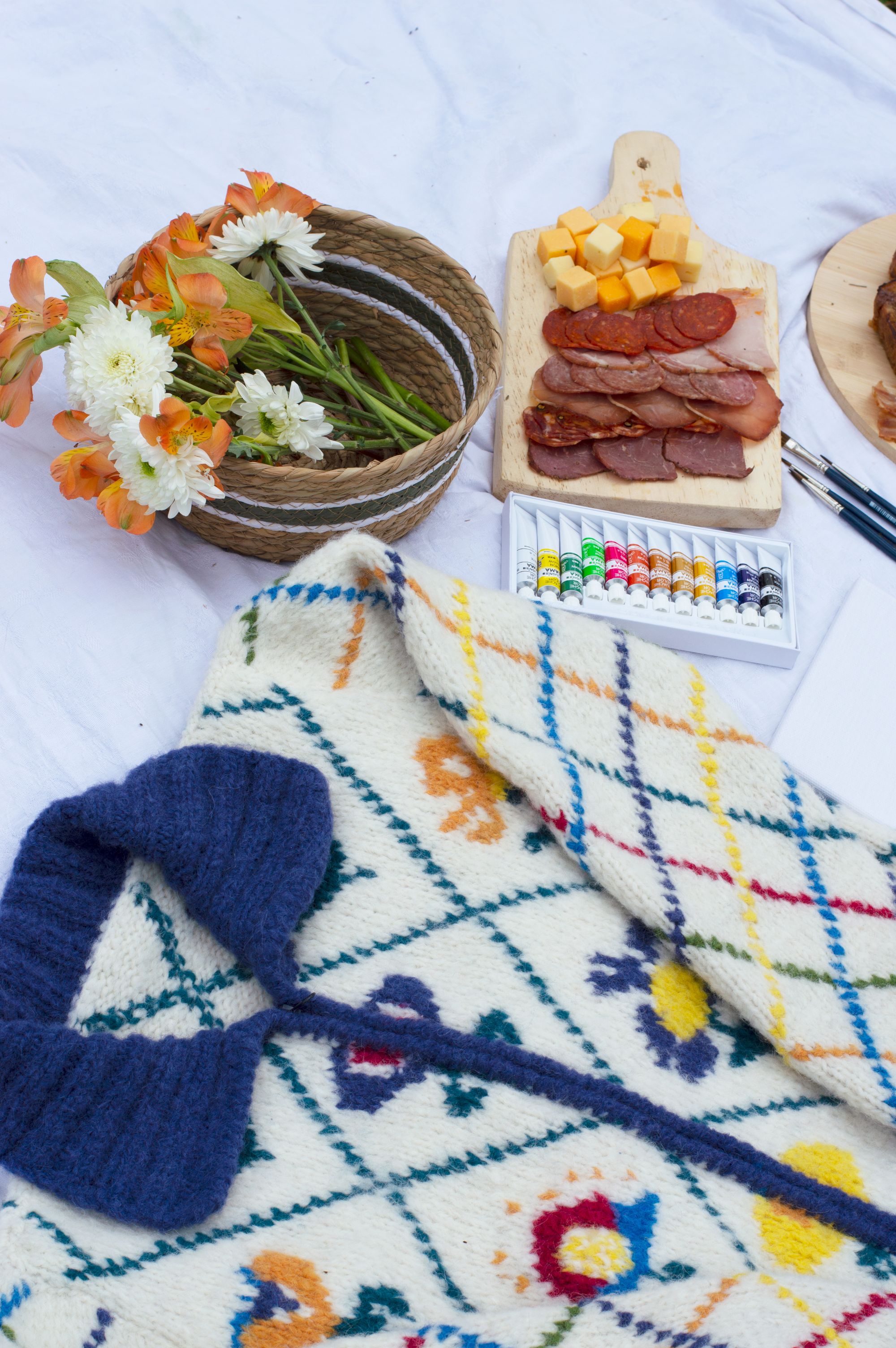 The Margaret cardigan laid out on a highland picnic with flowers and fruit
